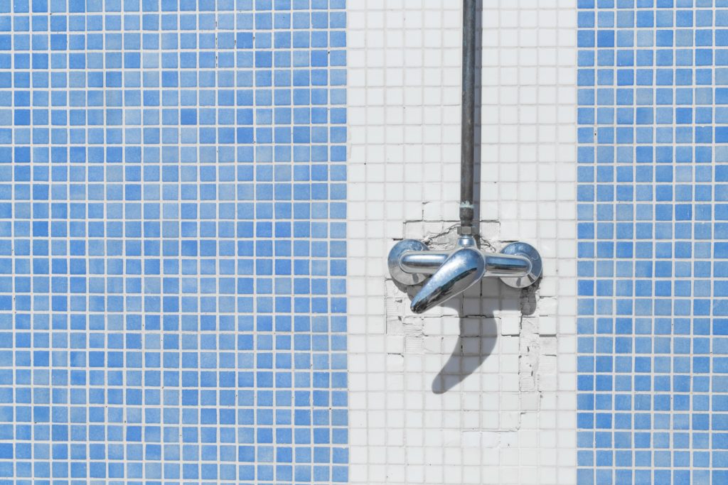 Shower faucet on white and blue mosaic tiles