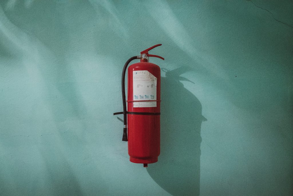 red fire extinguisher in front of blue wall