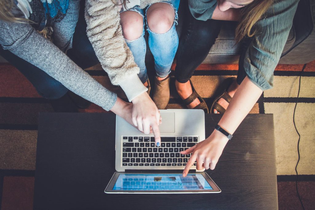 Three women working on same laptop