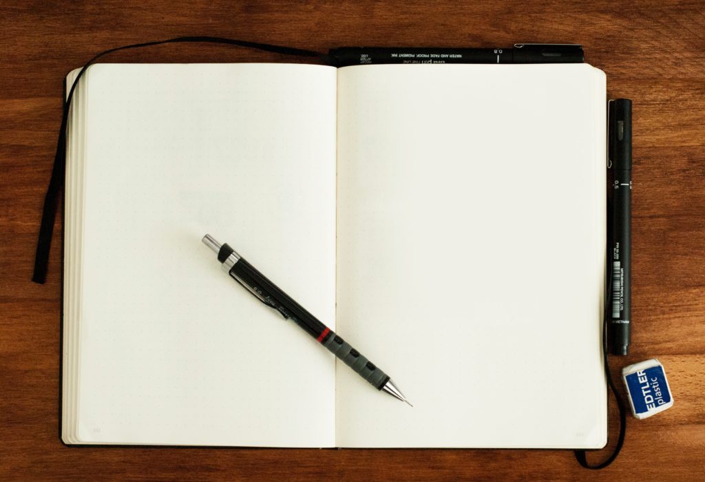 Empty notebook with blank pages, open, with pencil on top