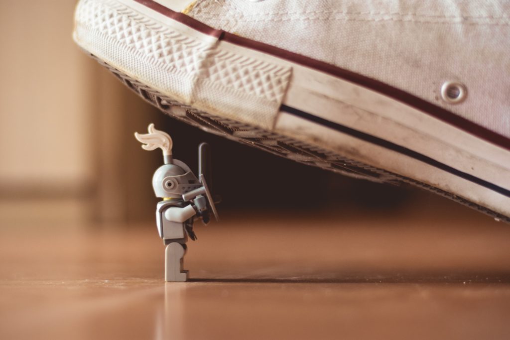 Grey lego knight figure about to get trampled by white sneaker 