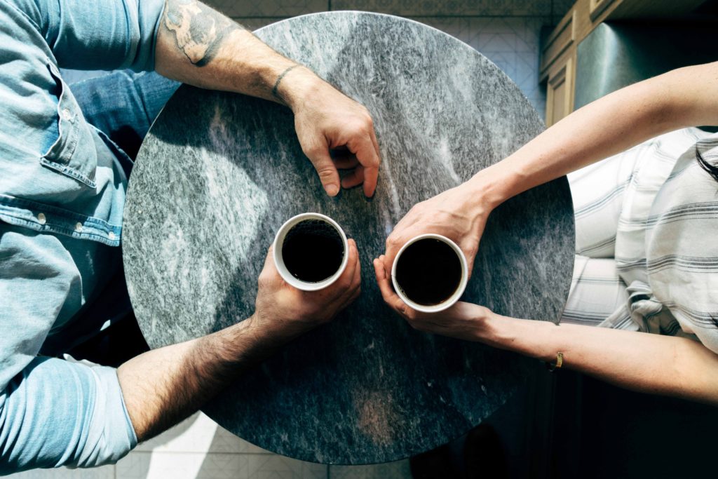 Table from above with two friends drinking coffee who exchange PhD experiences