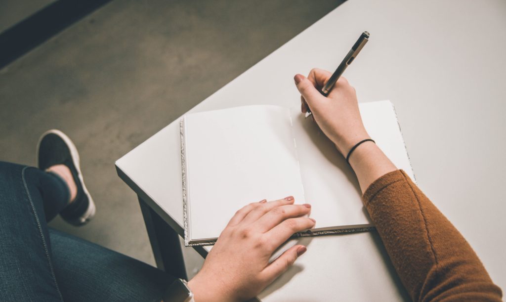 Person writing down notes in a note book