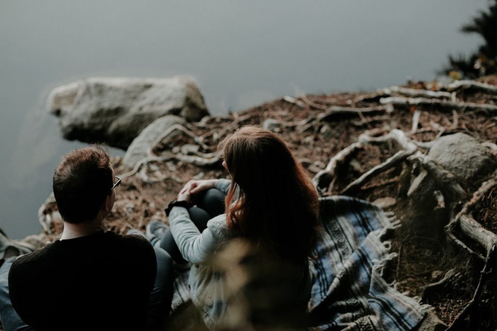 Two people sitting at a river bank talking